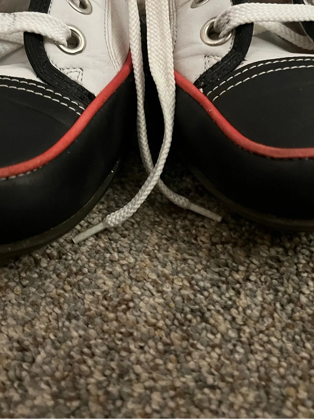 Donald J Pliner white canvas and black leather sneakers with red trim.
